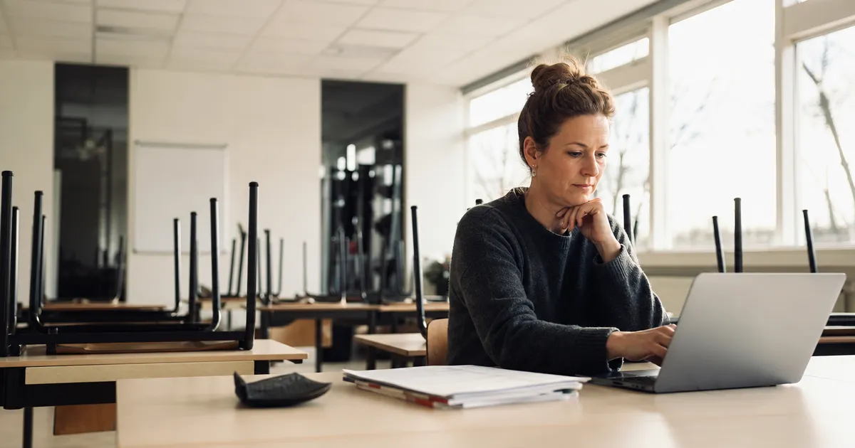 Docent bereidt lesmateriaal voor op een laptop in een leeg klaslokaal: vijf praktische AI-toepassingen in het onderwijs