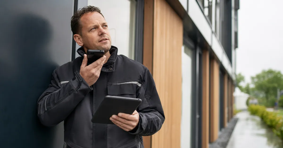 Inspecteur met notitieblok en telefoon bij een gevel, aantekeningen omzetten naar een AI-verslag